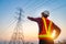 An electrical engineer standing and pointing at high voltage pylon To see the planning work by generating electric power and