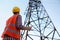 Electrical engineer with walkie talkie near high voltage tower, low angle view