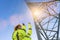 Electrical female engineer talking in a walkie talkie and pointing to control a high voltage electricity pylon. Close-up