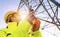 Electrical female engineer watching up and uses a walkie talkie to control a high voltage electricity pylon. Electrical power