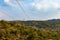 Electrical high volatge power line tower pillar on meadow hill area in front of blue sky and clouds