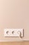 Electrical outlets with plug on beige wall