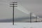 Electrical power lines with hoarfrost on the wooden electric poles on countryside in the winter,