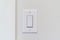 Electrical rocker light switch with flat broad lever on white interior wall