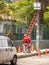 Electrical Technicians in Red Uniforms Prepare to Climb a Red Ladder to Fix an Electrical Box