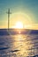 Electrical tower on a snowy field. Sun goes down, orange colors, evening scenery