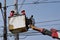 Electrical Workers On Telehandler With Bucket installing High tension wires on tall concrete post. Underside view low angle