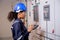 Electrical young asian woman engineer examining maintenance cabinet system electric and using tablet in control room.