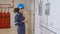 Electrical young asian woman engineer examining maintenance cabinet system electric and using tablet in control room.