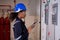 Electrical young asian woman engineer examining maintenance cabinet system electric and using tablet in control room.