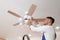 Electrician changing light bulb in ceiling fan indoors