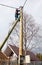 Electrician connects wires on a pole in a country house