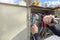 An electrician connects wires in a switchboard outdoors. The hands of an electrician close-up inserts the wire into the