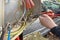 An electrician connects wires in a switchboard outdoors. The hands of an electrician close-up with pliers tightens the