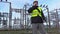 Electrician engineer walking and using smart phone near substation in winter
