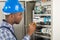 Electrician Examining Fusebox With Screwdriver