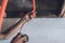 An electrician or handyman is inserting a wire inside an orange PVC corrugated electrical flexible hose