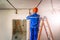 Electrician in hard hat and uniform standing on ladder