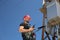 Electrician in red helmet and safety belt with radio station on the electric pole