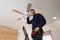 Electrician repairing ceiling fan with lamps indoors