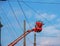 Electrician repairing wire of the power line with bucket hydraulic lifting platform on blue sky