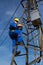 Electrician with safety belt working on electric power pole