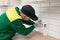 An electrician with a screwdriver assembles a socket in a kitchen wall lined with ceramic tiles