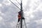 Electrician or telecommunications lineman works on laying a cable at the top of a telephone pole