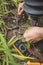 An electrician tests an exposed grounded wire with a digital multimeter with LCD screen. Safety procedure at a home garden