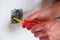 The electrician unscrews the switch with a screwdriver. Close-up on the hands. The routine work of an electrician. Checking