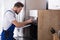 Electrician Writing On Clipboard In Front Of Oven