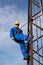 Electrician with yellow helmet and safety belt climbs the pole