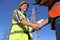 Electricians shaking hands near high voltage tower, closeup