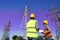 Electricians in uniforms near high voltage towers