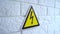 Electricity danger a sign on yellow background. A danger sign hangs on a wall. 4k stock footage.