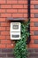 The electricity meter hangs on the brick wall of a private residential building.