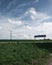 Electricity poles on green famlands next to a rural road and a street sign with the name of the nearby lake SvaneholmssjÃ¶n on a