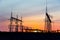 Electricity poles at sunset. High voltage grid towers with wire cable at distribution station