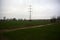 Electricity pylon in a cultivated field next to a highway on a cloudy day in the italian countryside