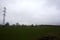 Electricity pylon in a cultivated field next to a highway on a cloudy day in the italian countryside