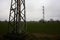 Electricity pylon in a cultivated field next to a highway on a cloudy day in the italian countryside