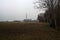 Electricity pylon in a cultivated field next to a highway on a cloudy day in the italian countryside