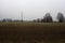 Electricity pylon in a cultivated field next to a highway on a cloudy day in the italian countryside