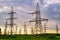 Electricity pylons bearing the power supply across a rural landscape. Orange sunset. Selective focus.