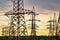 Electricity pylons bearing the power supply across a rural landscape during sunset. Selective focus.