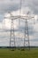 Electricity pylons and cable lines against cloudy sky