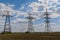 Electricity pylons going into the distance over summertime countryside.