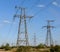 Electricity pylons going into the distance over summertime countryside.