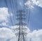 Electricity transmission lines and pylon silhouetted against blue sky and cloud,high voltage tower