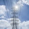 Electricity transmission lines and pylon silhouetted against blue sky and cloud,high voltage tower , light and flare effect added